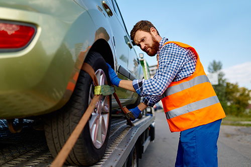 Driver securing a car onto a recovery truck for collection